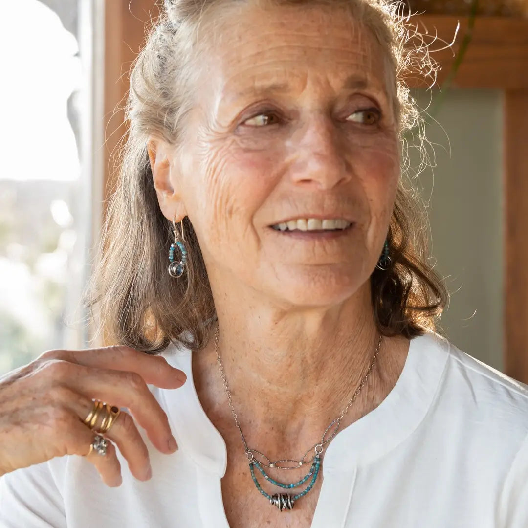 Faceted apatite gemstones form a ring that holds onto and oxidized sterling silver hand formed knot earring