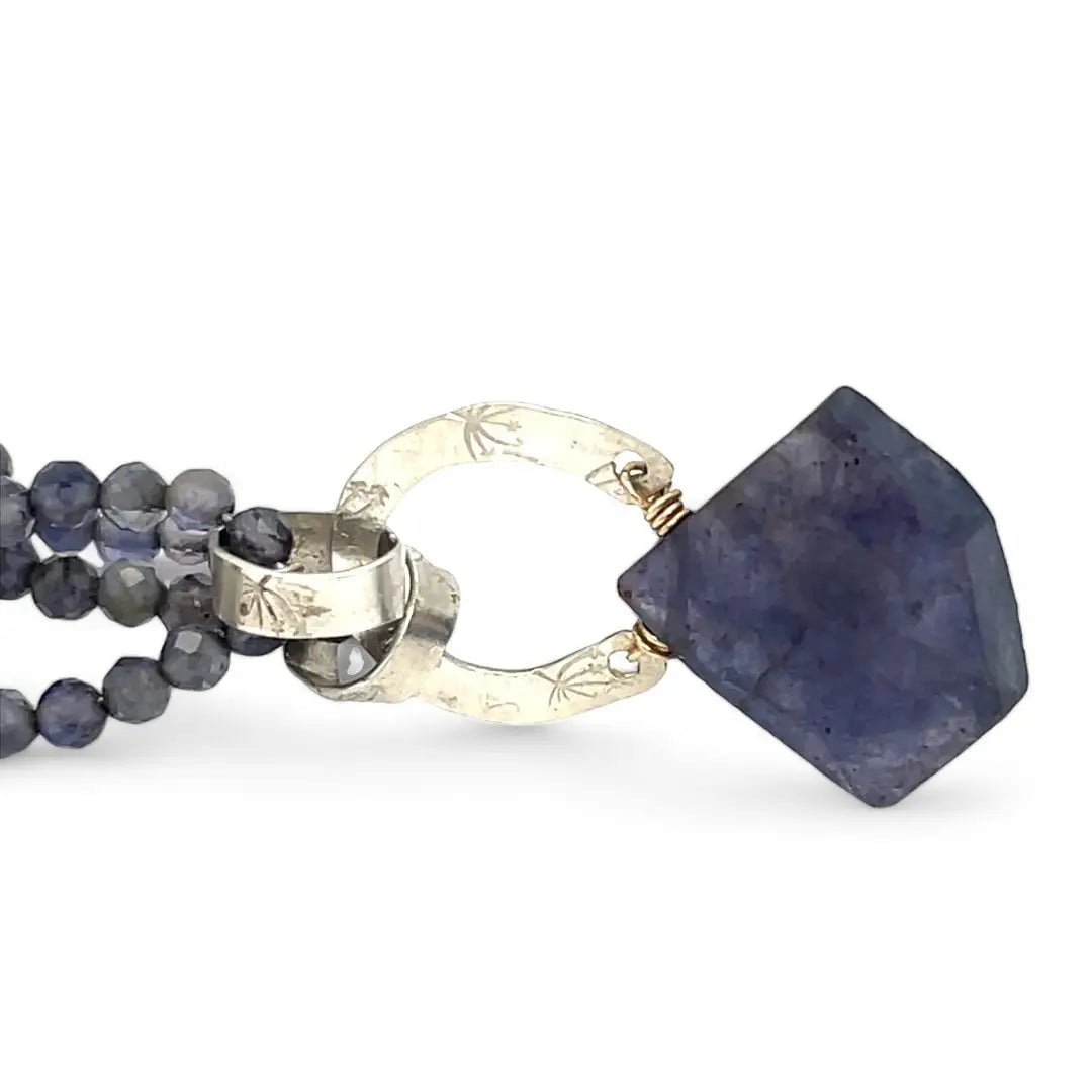 An iolite gemstone chain necklace with sterling silver hammered and stamped rings, featuring peacock freshwater pears and blue goldstone accents