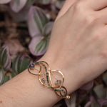 moss agate, green amethyst, and crystal gemstones are braided within waves of hammered brass, bronze, and sterling silver to form a braided cuff bracelet