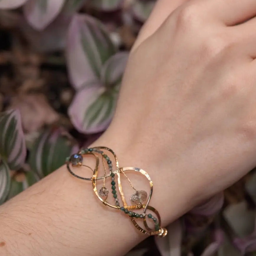 moss agate, green amethyst, and crystal gemstones are braided within waves of hammered brass, bronze, and sterling silver to form a braided cuff bracelet