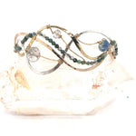 moss agate, green amethyst, and crystal gemstones are braided within waves of hammered brass, bronze, and sterling silver to form a braided cuff bracelet