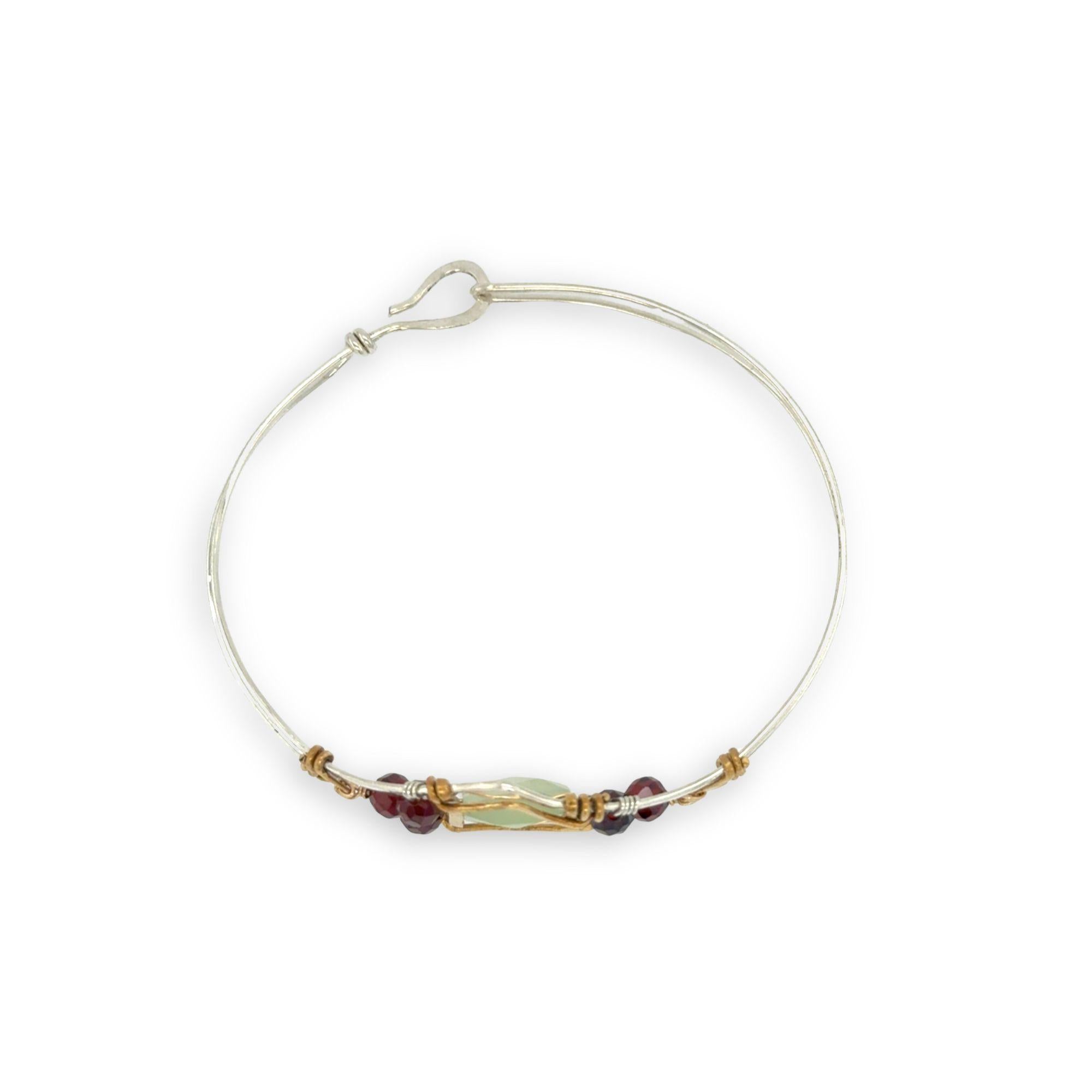 Sterling silver cuff bracelet with faceted serpentine jade rectangle at the center surrounded by faceted garnet gemstones and brass hammered wire