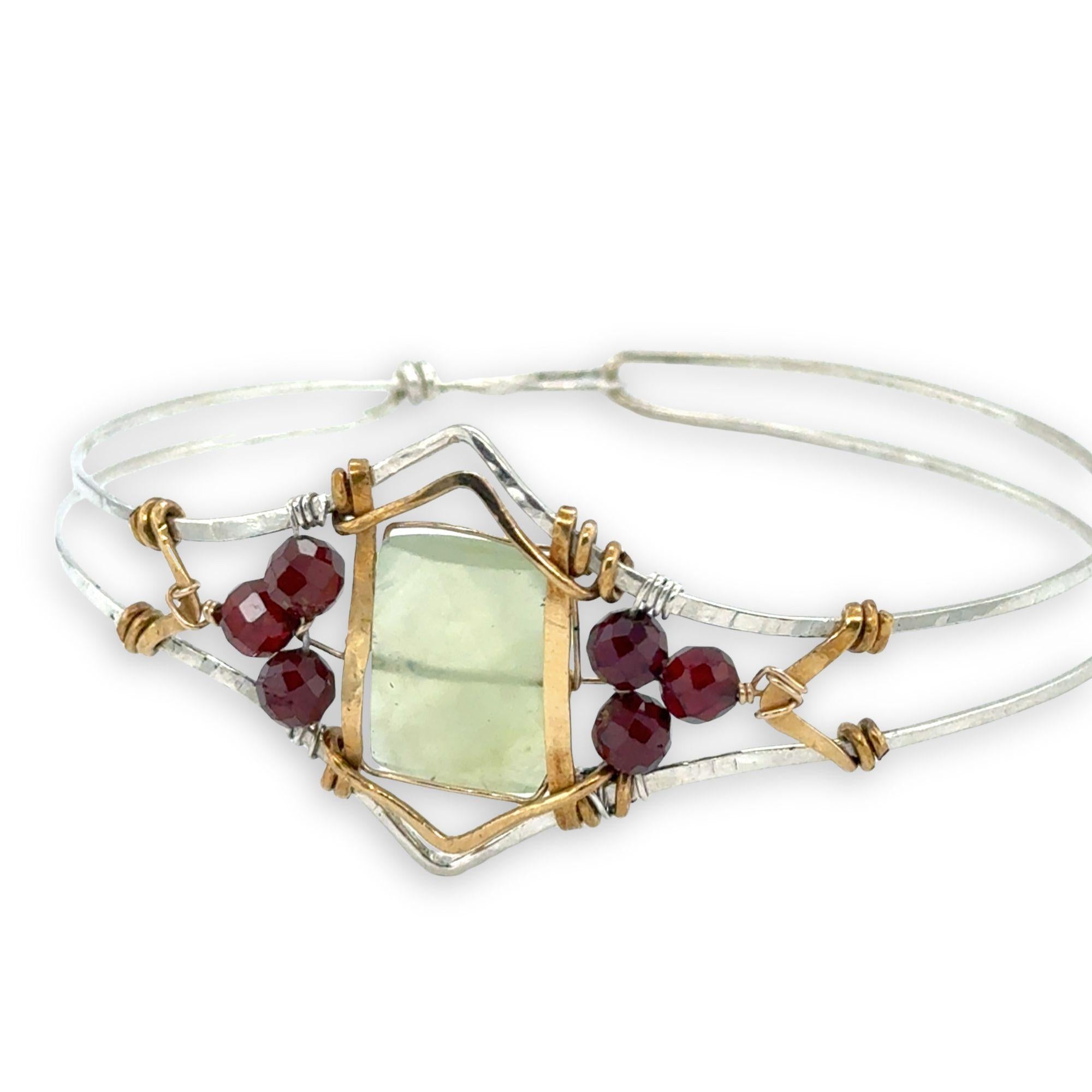 Sterling silver cuff bracelet with faceted serpentine jade rectangle at the center surrounded by faceted garnet gemstones and brass hammered wire