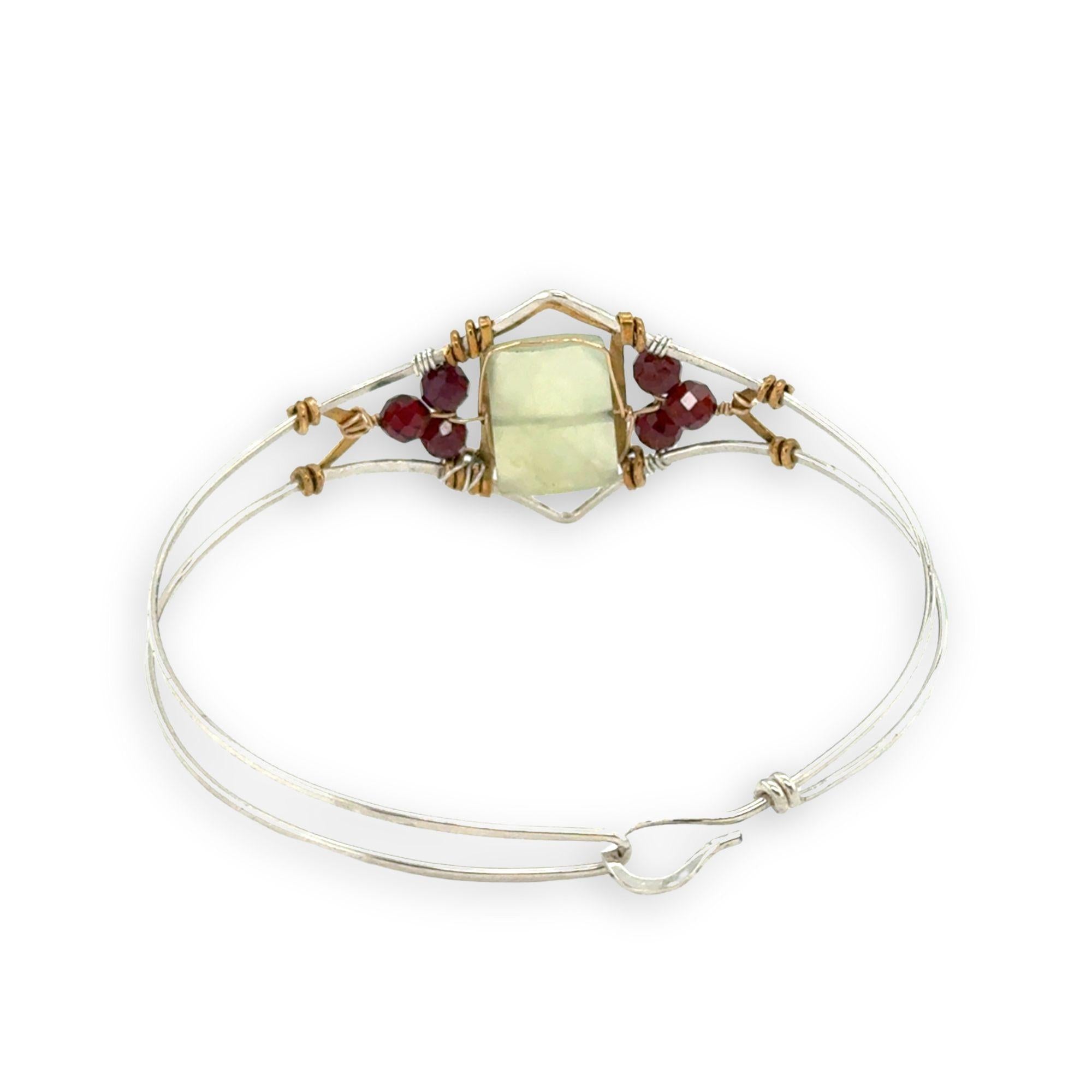 Sterling silver cuff bracelet with faceted serpentine jade rectangle at the center surrounded by faceted garnet gemstones and brass hammered wire