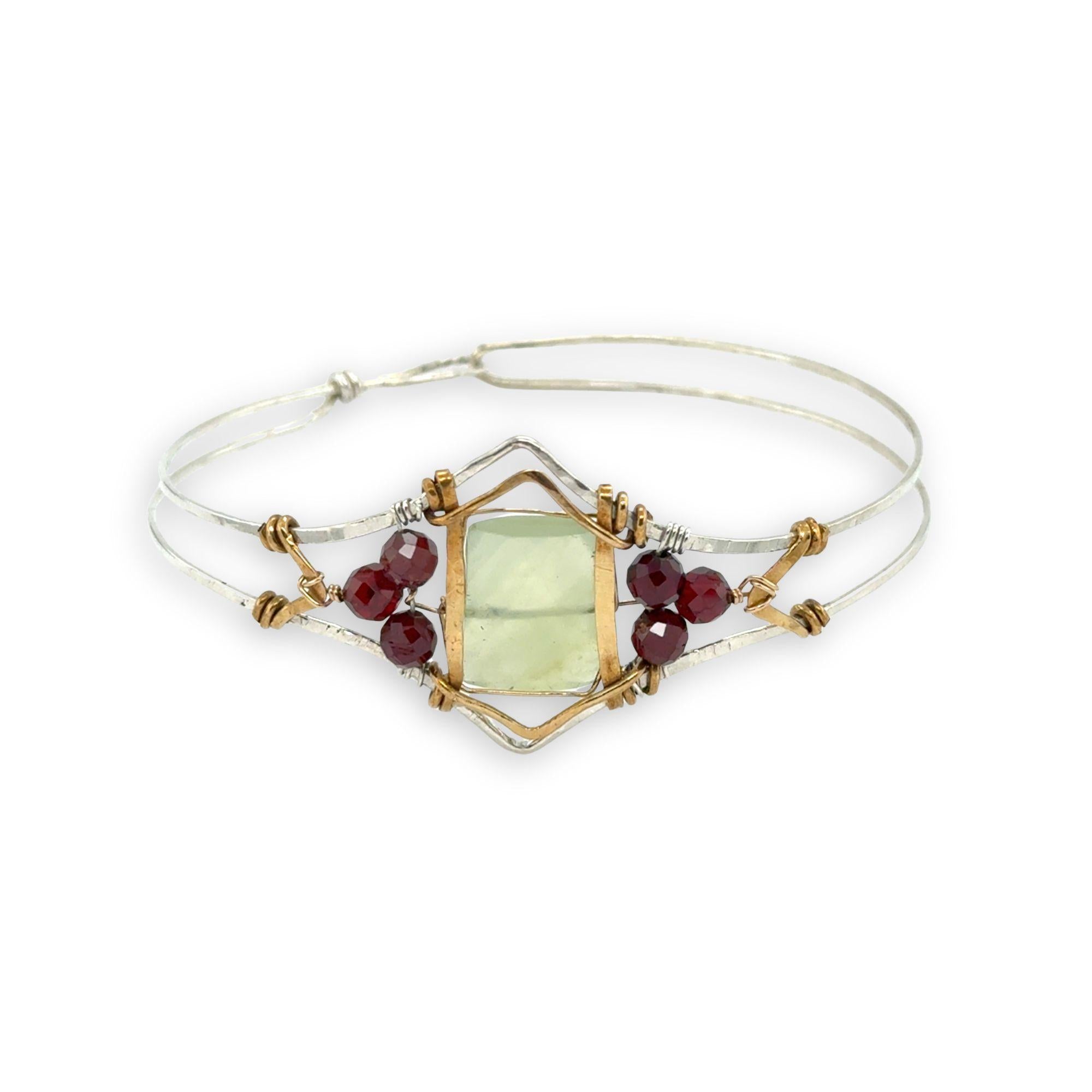 Sterling silver cuff bracelet with faceted serpentine jade rectangle at the center surrounded by faceted garnet gemstones and brass hammered wire