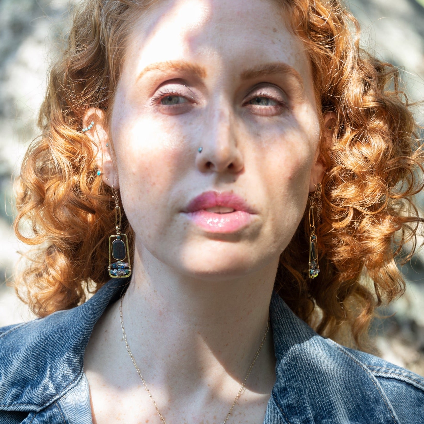 Smooth kyanite gemstones are accented with crystal cubes and blue tourmaline gemstones inside a brass rectangle earrings