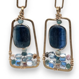 Smooth kyanite gemstones are accented with crystal cubes and blue tourmaline gemstones inside a brass rectangle earrings