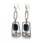 Smooth kyanite gemstones are accented with crystal cubes and blue tourmaline gemstones inside a brass rectangle earrings
