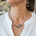 Brass crescent necklace on oxidized sterling silver tube chain with blue kyanite slice, mauve moonstone drop, crystal, iolite, and tourmalinated quartz gemstones on sterling silver wire necklace