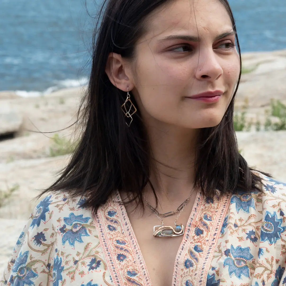 A double-layered necklace with a geometric design, featuring a rectangular darkened sterling silver pendant with a fluorite gemstone, flashy labradorite gemstone, and bronze accents, connected to chain links and additional bronze rings.