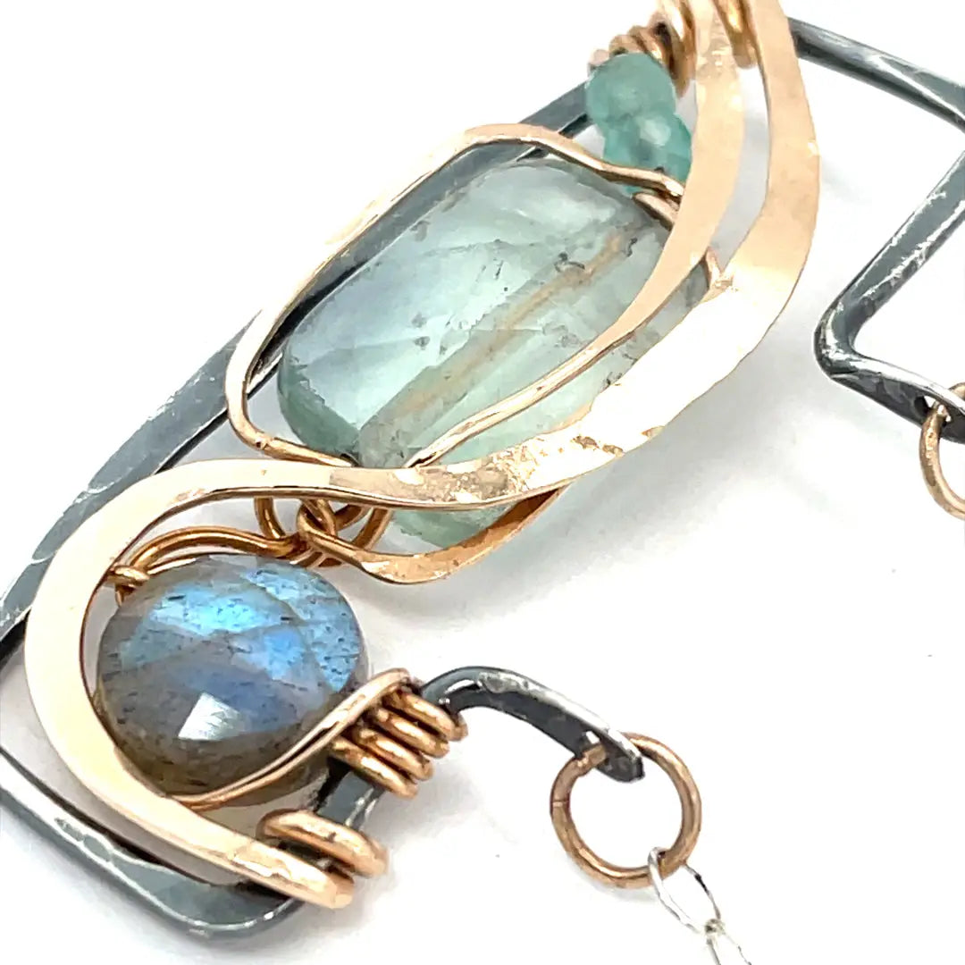 A double-layered necklace with a geometric design, featuring a rectangular darkened sterling silver pendant with a fluorite gemstone, flashy labradorite gemstone, and bronze accents, connected to chain links and additional bronze rings.
