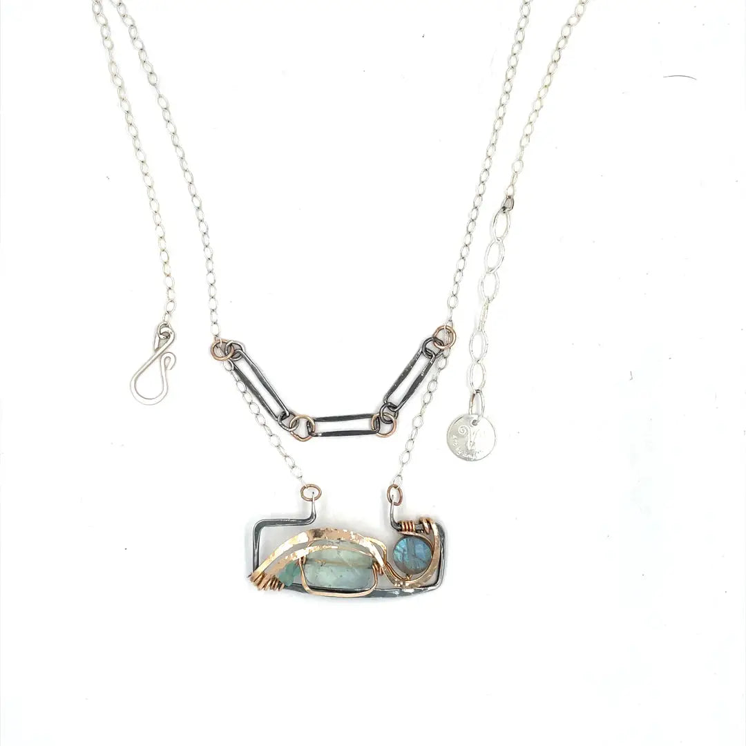 A double-layered necklace with a geometric design, featuring a rectangular darkened sterling silver pendant with a fluorite gemstone, flashy labradorite gemstone, and bronze accents, connected to chain links and additional bronze rings.