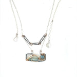 A double-layered necklace with a geometric design, featuring a rectangular darkened sterling silver pendant with a fluorite gemstone, flashy labradorite gemstone, and bronze accents, connected to chain links and additional bronze rings.