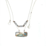 A double-layered necklace with a geometric design, featuring a rectangular darkened sterling silver pendant with a fluorite gemstone, flashy labradorite gemstone, and bronze accents, connected to chain links and additional bronze rings.