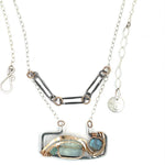 A double-layered necklace with a geometric design, featuring a rectangular darkened sterling silver pendant with a fluorite gemstone, flashy labradorite gemstone, and bronze accents, connected to chain links and additional bronze rings.