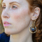 A pair of brass drop earrings featuring faceted lapis and sodalite gemstones and a crystal coin design, attached with gold filled and brass twist wires