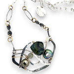 kambaba jasper, fresh water pearl. pyrite, and green kyanite gemstones are laid within layers of sterling silver and gold filled wire on a darkened sterling silver pendant necklace