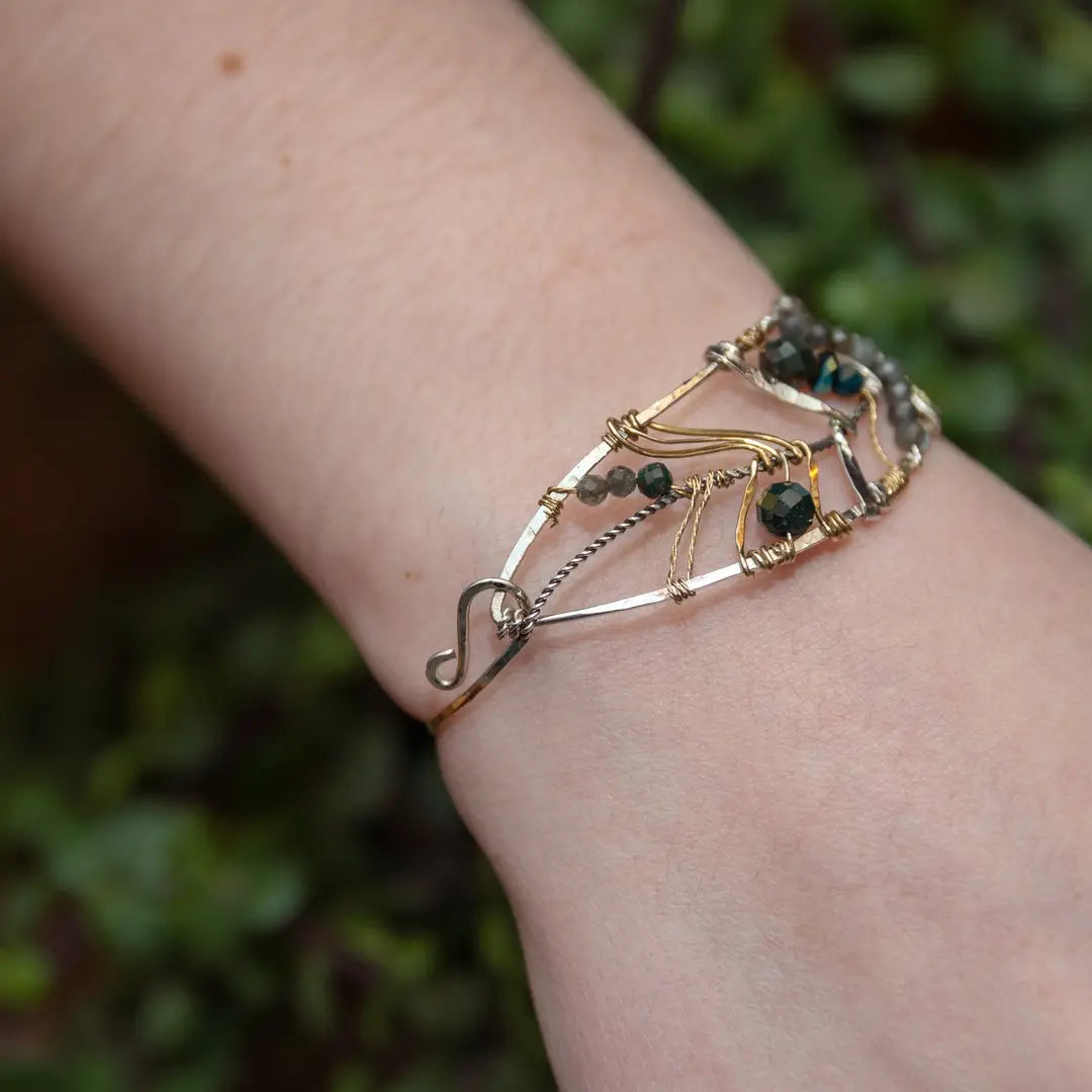 Bloodstone and labradorite faceted gemstones held within a sterling silver hand formed wave bracelet with oxidized sterling twist, gold filled wire and brass accents