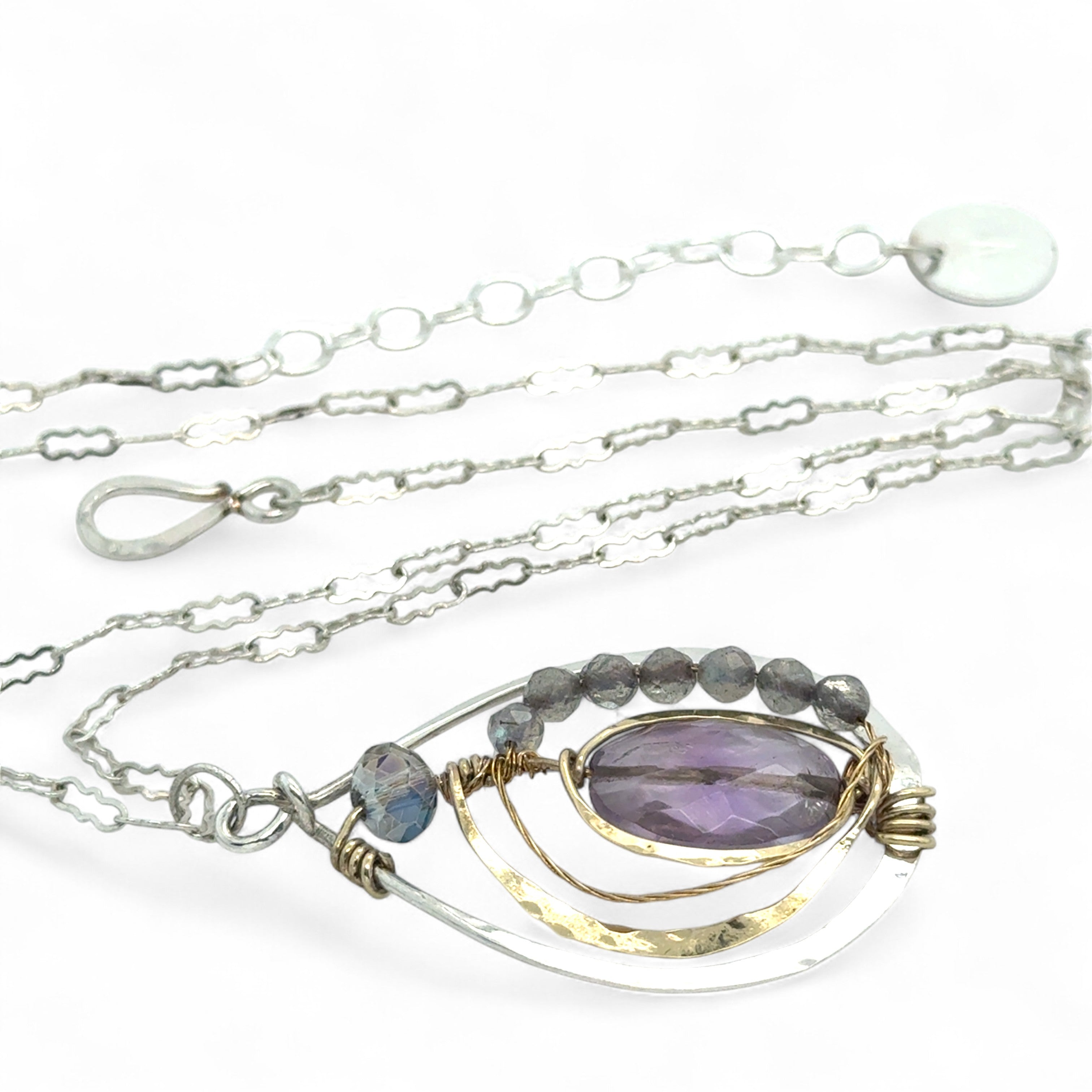 Teardrop-shaped sterling silver and brass pendatn with amethyst, labradorite, and crystal gemstones on delicate sterling silver chain