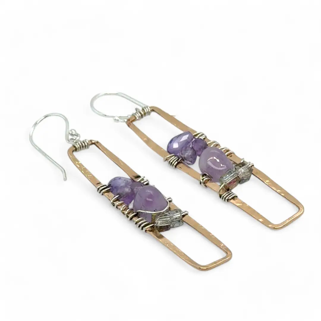 A pair of skinny tall bronze rectangle earrings with lilac purple amethyst pebbles, faceted amethyst gemstones, cubic zirconia purple drops, and crystal cubes stacked ontop of each other
