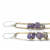 A pair of skinny tall bronze rectangle earrings with lilac purple amethyst pebbles, faceted amethyst gemstones, cubic zirconia purple drops, and crystal cubes stacked ontop of each other