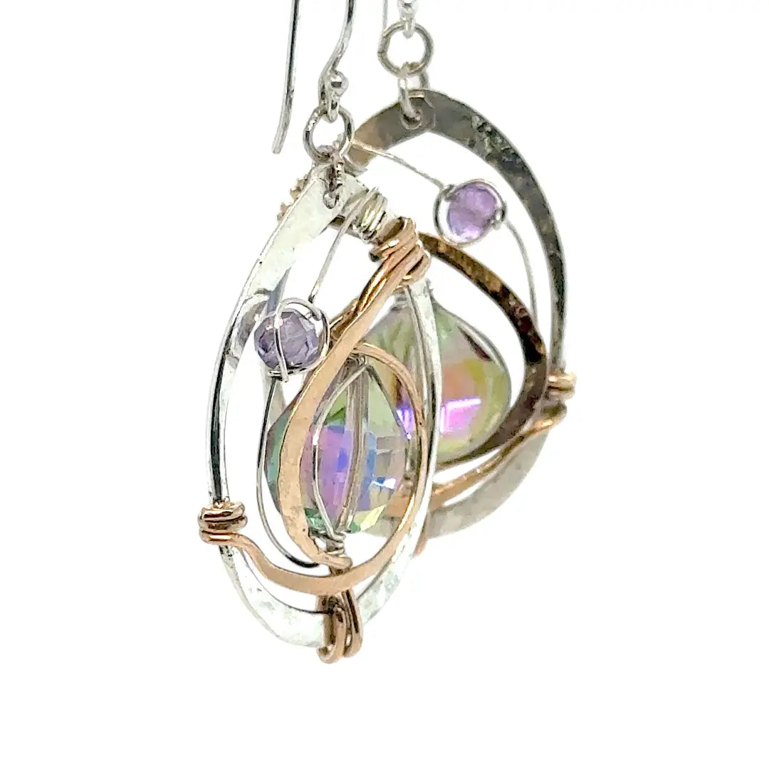 Hammered sterling silver oval earrings with hammered bronze accents holding and iridescent lilac crystal drop and amethyst gemstones
