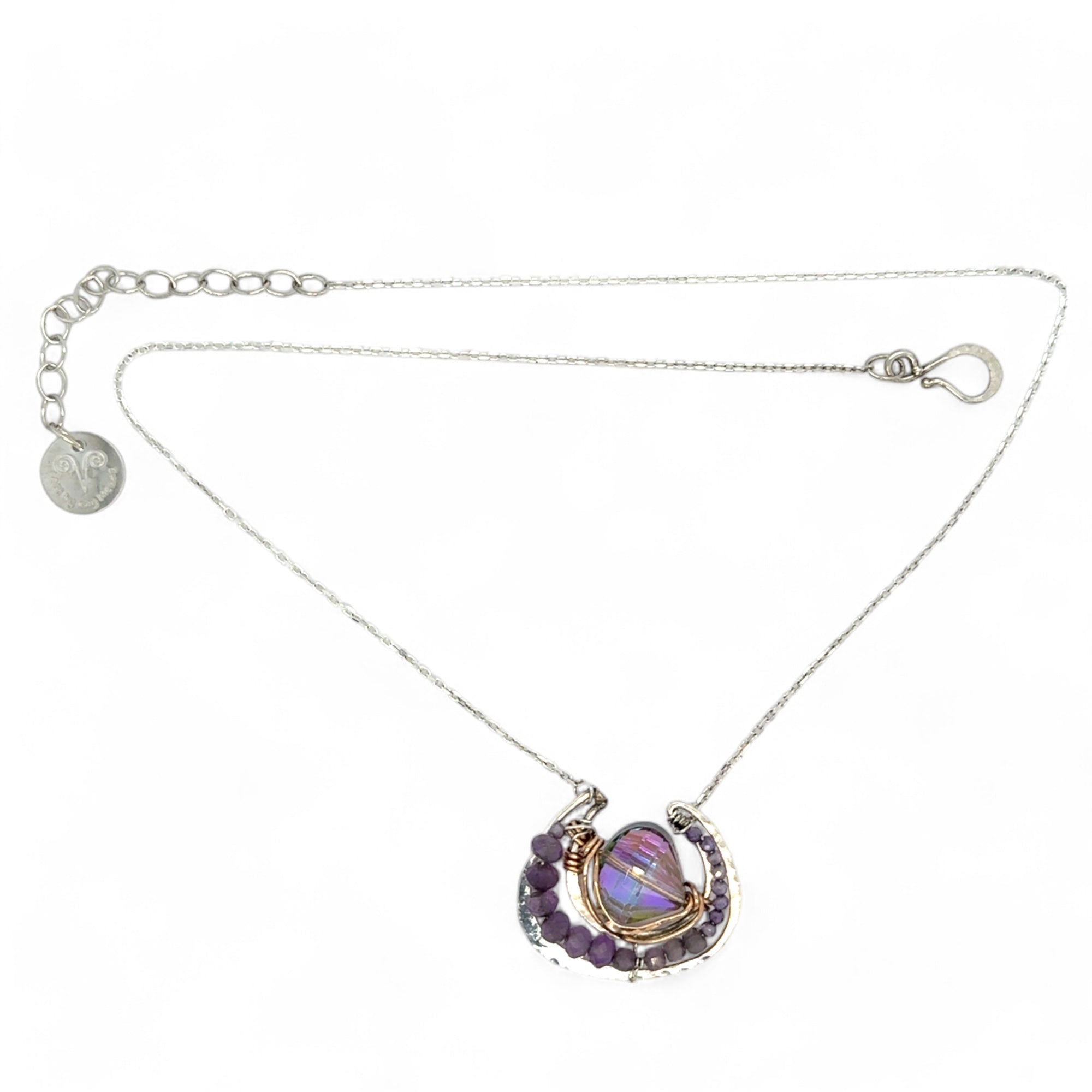 A lilac color iridescent crystal in a sterling silver channel pendant necklace with hammered bronze detailing, encrusted with faceted amethyst gemstones, on an adjustable sterling silver chain.