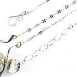 A darkened sterling silver moth-shaped pendant featuring a smooth cream agate gemstone, white sapphire, and jade drops, complemented by a fresh water pearl, with layers of gold filled and hammered brass wires