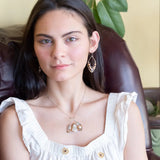 A darkened sterling silver moth-shaped pendant featuring a smooth cream agate gemstone, white sapphire, and jade drops, complemented by a fresh water pearl, with layers of gold filled and hammered brass wires