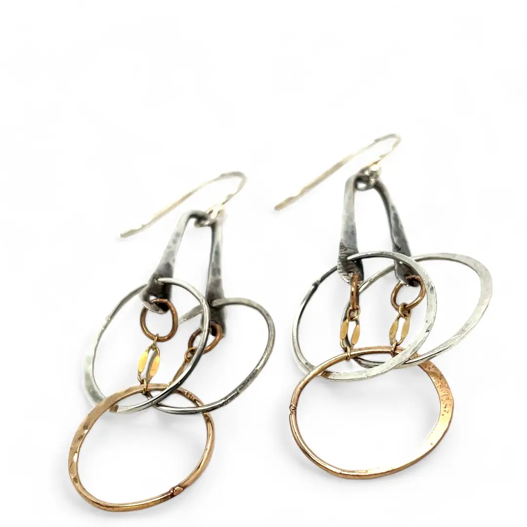 a pair of oxidized fern stamped arch earrings with sterling silver and bronze interlocked rings