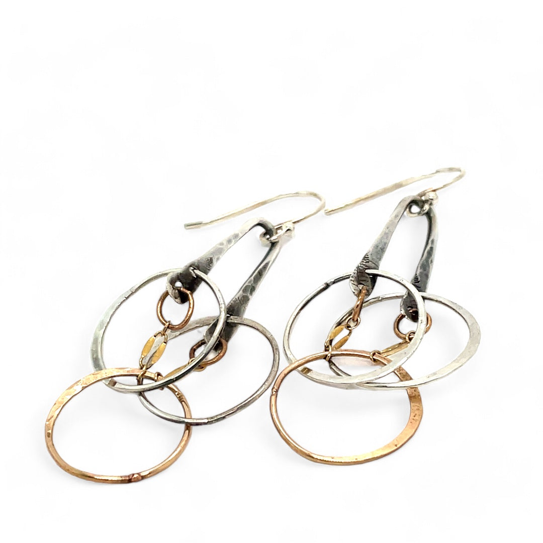 a pair of oxidized fern stamped arch earrings with sterling silver and bronze interlocked rings