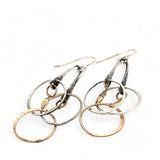 a pair of oxidized fern stamped arch earrings with sterling silver and bronze interlocked rings