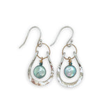 Mint fresh water pearl coin held within a stamped and hammered sterling silver open hoop hanging on a gold filled braided link