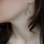 Mint fresh water pearl coin held within a stamped and hammered sterling silver open hoop hanging on a gold filled braided link