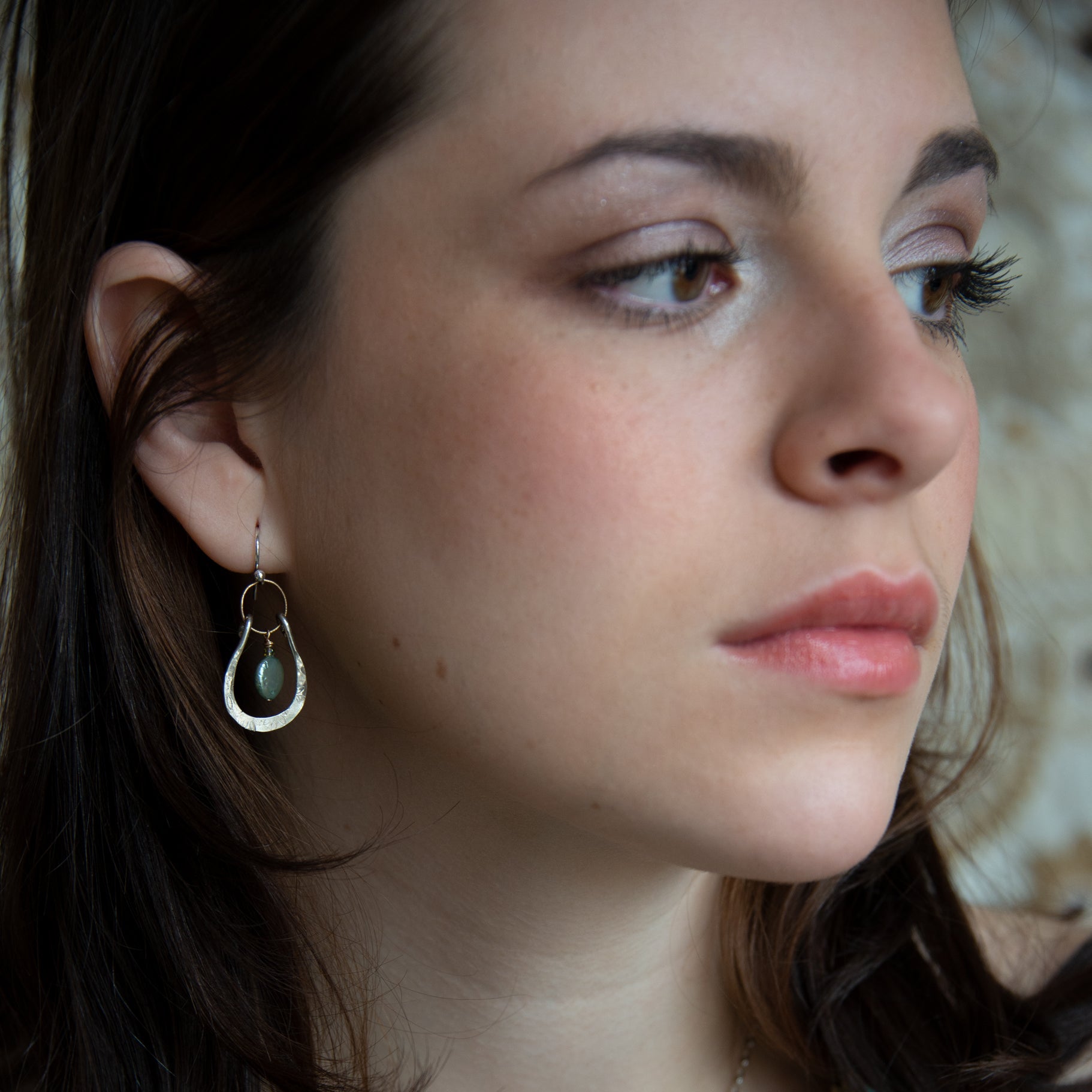 Mint fresh water pearl coin held within a stamped and hammered sterling silver open hoop hanging on a gold filled braided link