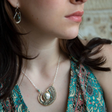 Mint fresh water pearl coin held within a brass pendant necklace filled with amazonite and crystal gemstones along side with oxidized sterling silver twist wire