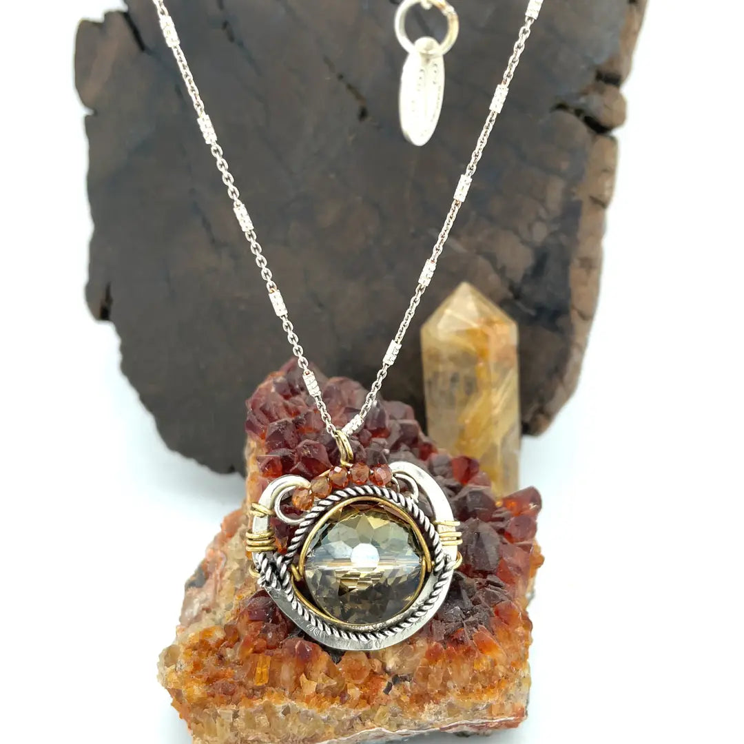 a metallic silver and gold crystal pendant necklace with a geometric design, with hessonite garnet accent and a sparkly sterling silver chain