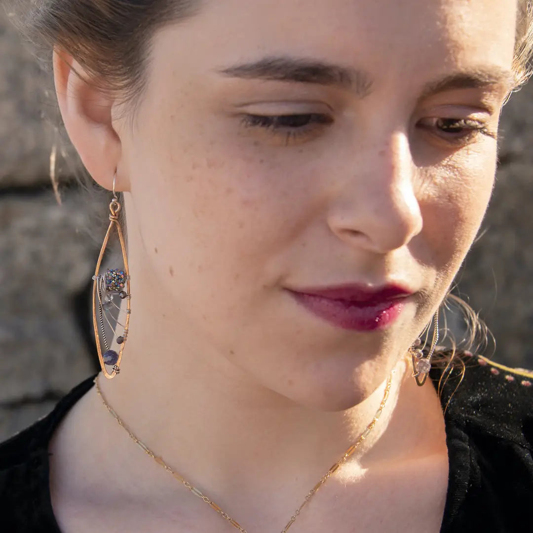 A pair of bronze marquise earrings, with iolite gemstones, and a central sparkling meteorite-like texture, suspended from sterling silver French hooks.
