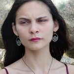 A pair of sterling silver hoop earringsthat have been stamped with dandelions and swirls, featuring a green fluorite smooth coin wrapped in gold filled wire and surrounded by a array of multicolored gemstones.