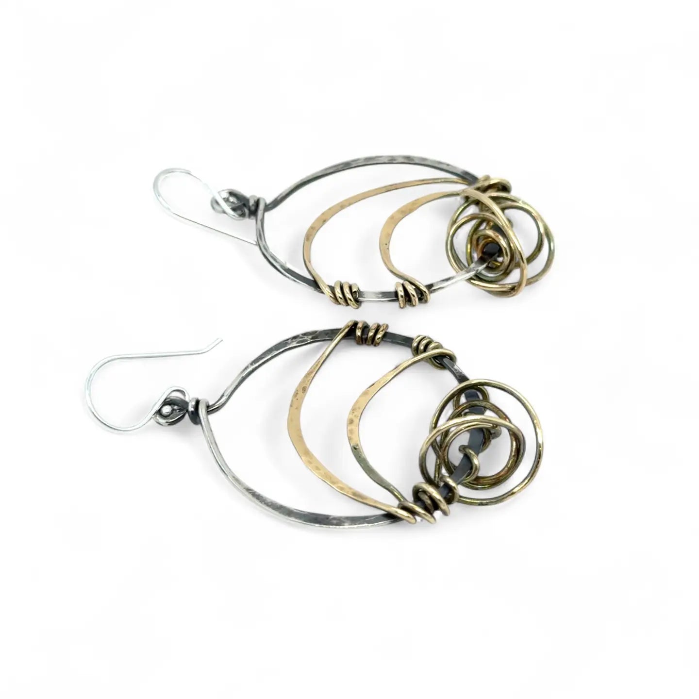 A pair of earrings featuring gestural knots of hand-formed hammered brass on oxidized sterling silver hoops