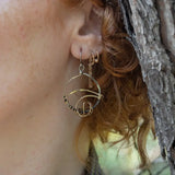 A pair of earrings featuring gestural knots of hand-formed hammered brass on oxidized sterling silver hoops
