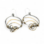 A pair of earrings featuring gestural knots of hand-formed hammered brass on oxidized sterling silver hoops