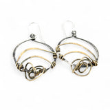 A pair of earrings featuring gestural knots of hand-formed hammered brass on oxidized sterling silver hoops