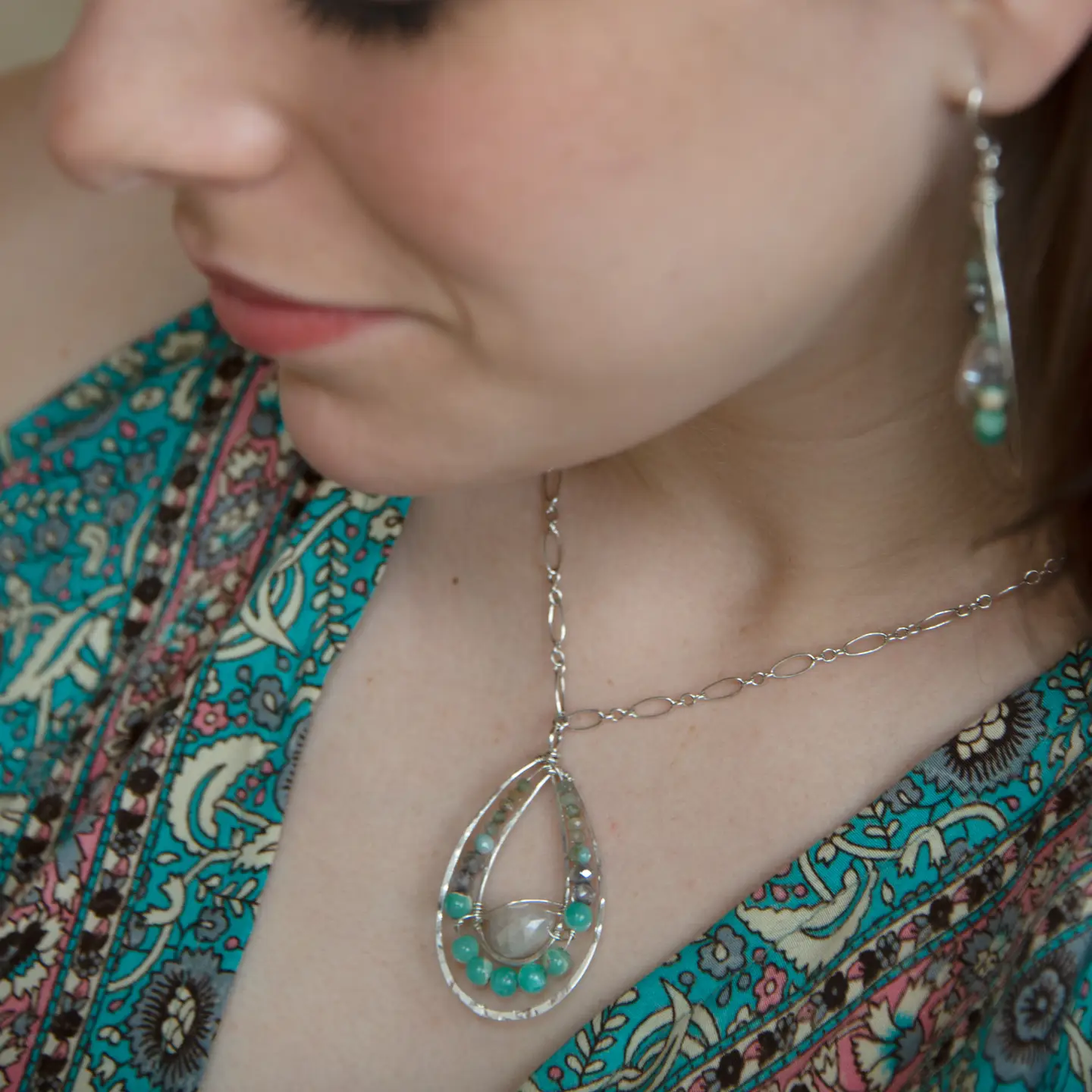 Moonstone drop gemstone held inside a sterling silver channel drop necklace lined with moss agate, amazonite, and terra verde jasper gemstones on a delicate sterling silver chain