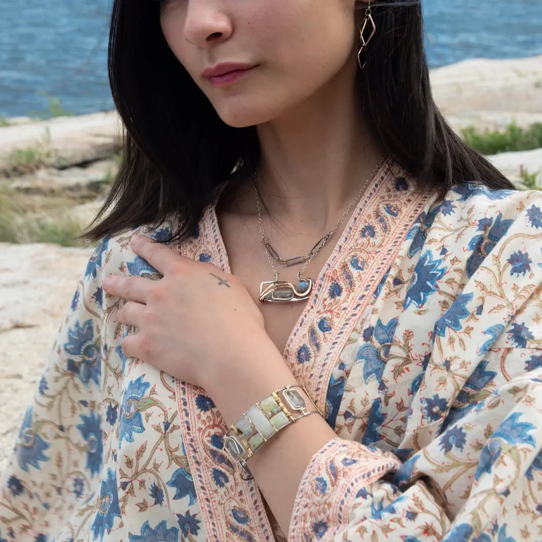 an oxidized sterling silver wide cuff bracelet with brass bars, featuring faceted moonstone, smooth prehnite, chalcedony, and fluorite gemstones on gold filled wire