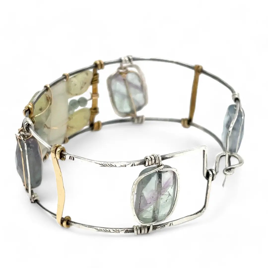 an oxidized sterling silver wide cuff bracelet with brass bars, featuring faceted moonstone, smooth prehnite, chalcedony, and fluorite gemstones on gold filled wire