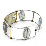 an oxidized sterling silver wide cuff bracelet with brass bars, featuring faceted moonstone, smooth prehnite, chalcedony, and fluorite gemstones on gold filled wire
