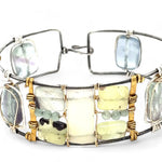an oxidized sterling silver wide cuff bracelet with brass bars, featuring faceted moonstone, smooth prehnite, chalcedony, and fluorite gemstones on gold filled wire