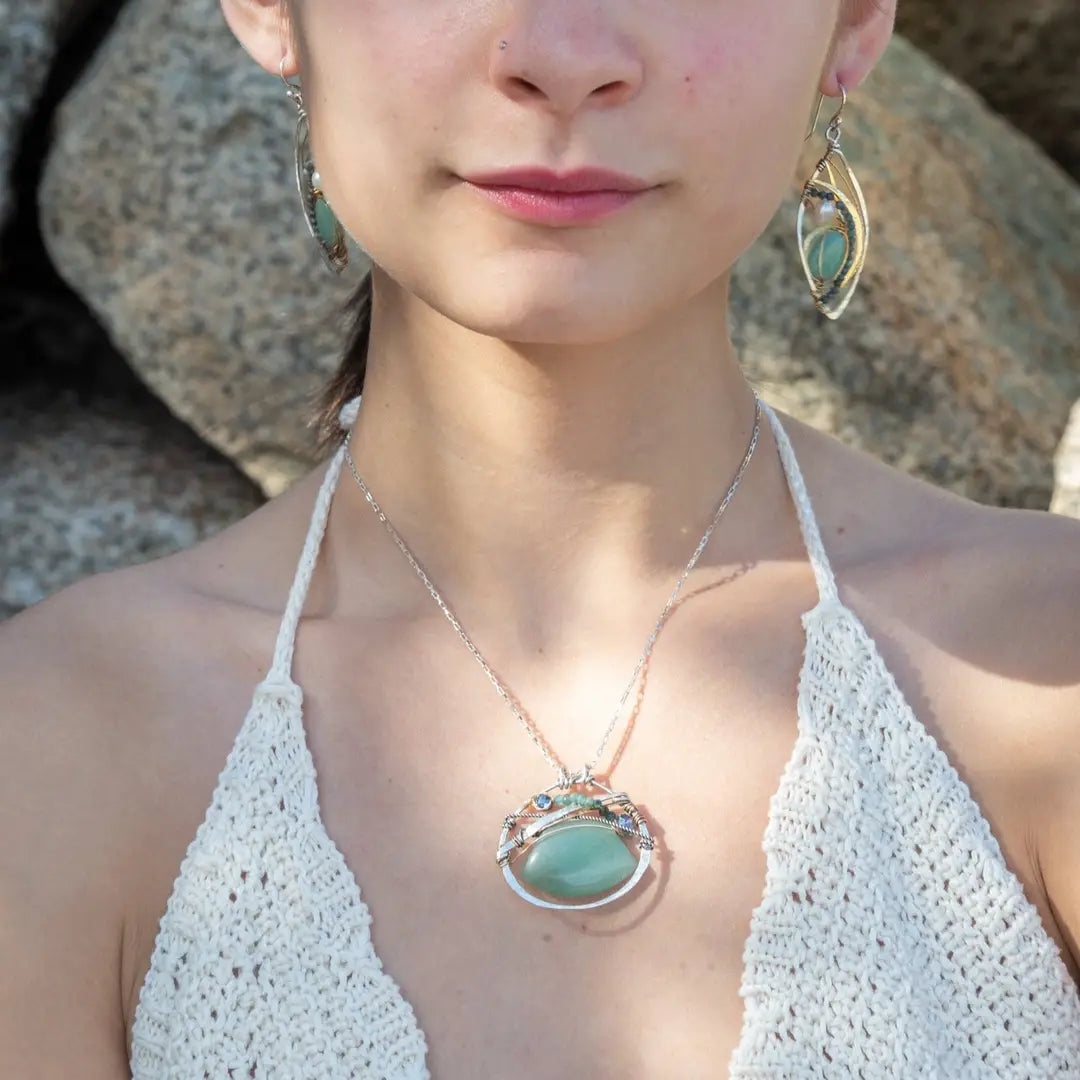 A sterling silver necklace with a moss-colored jade fan gemstone pendant featuring hammered bronze, oxidized sterling silver twist wire, and micro faceted ombre blue tourmaline gemstones, crystal, and pyrite.