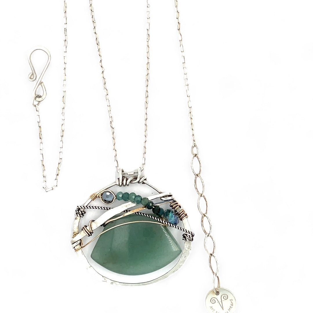 A sterling silver necklace with a moss-colored jade fan gemstone pendant featuring hammered bronze, oxidized sterling silver twist wire, and micro faceted ombre blue tourmaline gemstones, crystal, and pyrite.